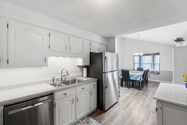 9513 Sequoia Ct, Affton, MO 63123 - kitchen featuring stainless steel appliances, a sink, light wood finished floors, a textured ceiling, and a chandelier