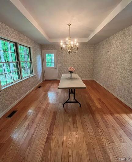 16453 Scenic Ridge Rd, Marthasville, MO 63357 - unfurnished dining area with a raised ceiling, wallpapered walls, wood finished floors, and a chandelier