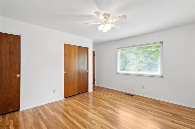 13105 Dartagnan Ct, Creve Coeur, MO 63141 - unfurnished bedroom with light wood finished floors, baseboards, a ceiling fan, and multiple closets