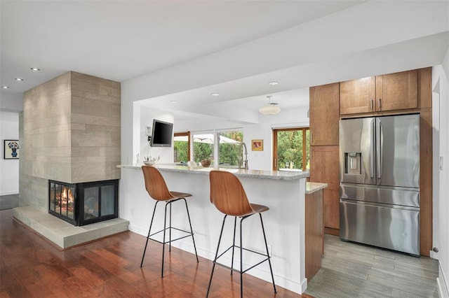 36 Stoneyside Ln, Olivette, MO 63132 - kitchen with stainless steel fridge with ice dispenser, brown cabinetry, light wood-type flooring, a kitchen bar, and recessed lighting