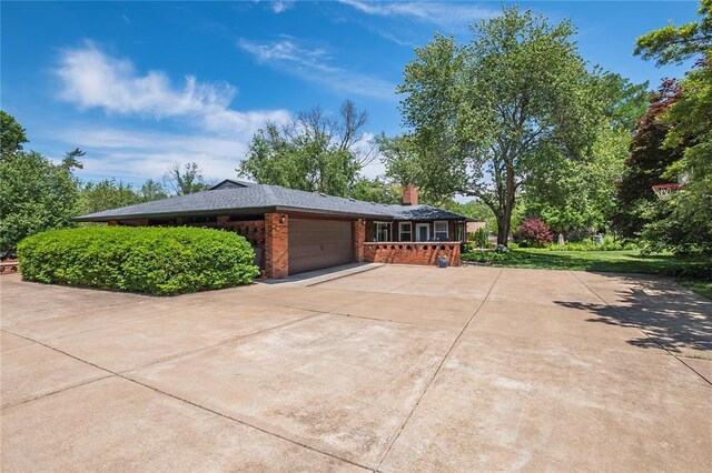 23 Vouga Ln, Frontenac, MO 63131 - view of property exterior featuring a garage, a chimney, driveway, and brick siding