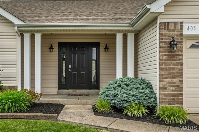 403 Autumn Farms Ct, Wentzville, MO 63385 - entrance to property with a shingled roof, a garage, brick siding, and covered porch
