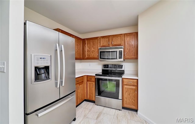 9 Homefield Gardens Dr Unit 31N, Ofallon, MO 63366 - kitchen featuring appliances with stainless steel finishes, light countertops, brown cabinetry, and light marble finish flooring