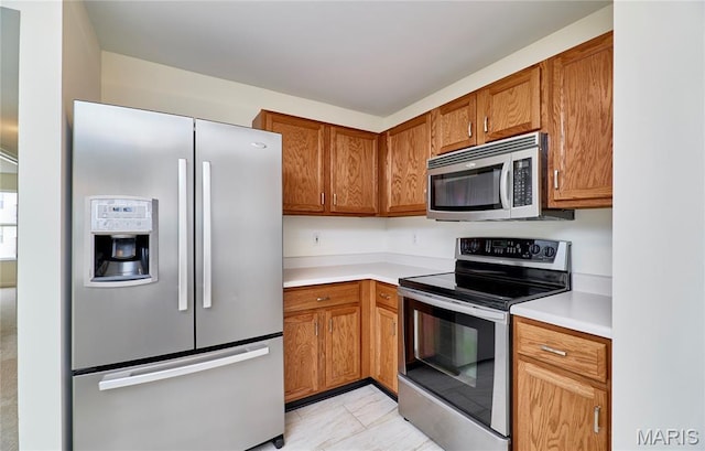 9 Homefield Gardens Dr Unit 31N, Ofallon, MO 63366 - kitchen with appliances with stainless steel finishes, light countertops, brown cabinetry, and light tile patterned flooring
