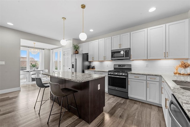 3516 Broad St, Saint Charles, MO 63301 - kitchen with stainless steel appliances, a breakfast bar, wood finished floors, tasteful backsplash, and recessed lighting