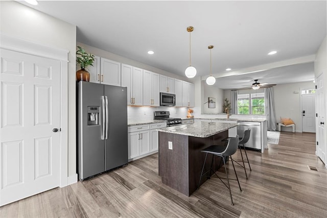 3516 Broad St, Saint Charles, MO 63301 - kitchen with appliances with stainless steel finishes, a peninsula, a sink, a kitchen island, and light wood-type flooring