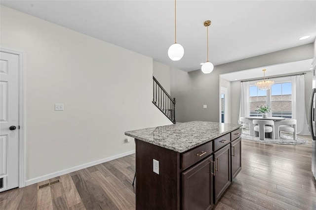3516 Broad St, Saint Charles, MO 63301 - kitchen featuring a chandelier, dark brown cabinets, wood finished floors, decorative light fixtures, and light stone counters