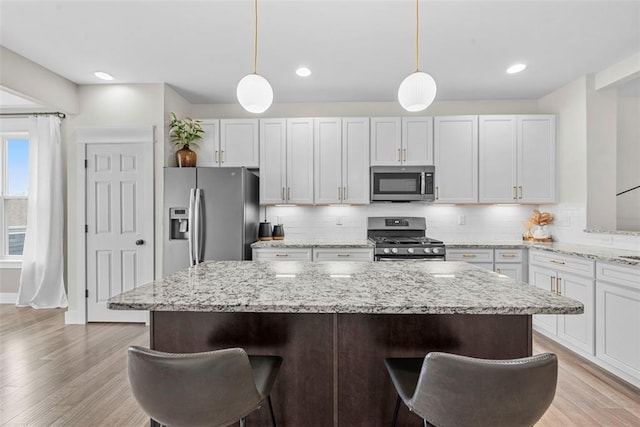 3516 Broad St, Saint Charles, MO 63301 - kitchen featuring stainless steel appliances, a breakfast bar, a kitchen island, tasteful backsplash, and recessed lighting