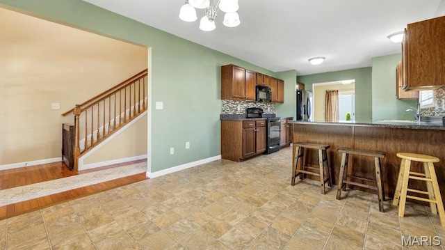 1101 Gulfstream Way, Mascoutah, IL 62258 - kitchen featuring black appliances, a kitchen breakfast bar, a chandelier, dark countertops, and backsplash