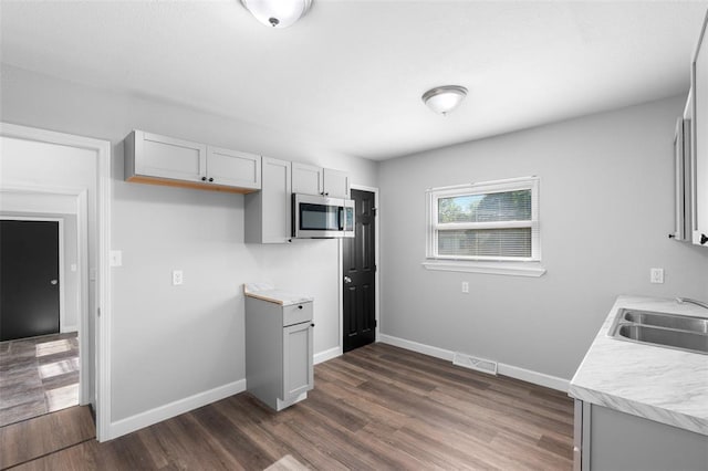 418 Williams St, Pacific, MO 63069 - kitchen featuring stainless steel microwave, a sink, light countertops, dark wood-style floors, and baseboards