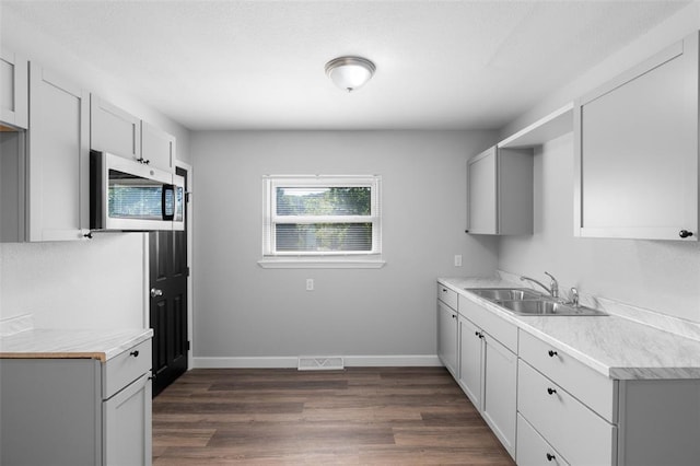 418 Williams St, Pacific, MO 63069 - kitchen with a sink, stainless steel microwave, light countertops, dark wood-type flooring, and baseboards