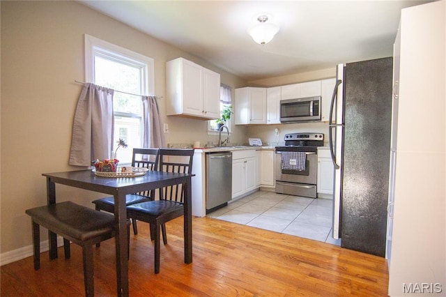 108 Tomlinson St, East Alton, IL 62024 - kitchen featuring stainless steel appliances, white cabinetry, and light wood-style flooring