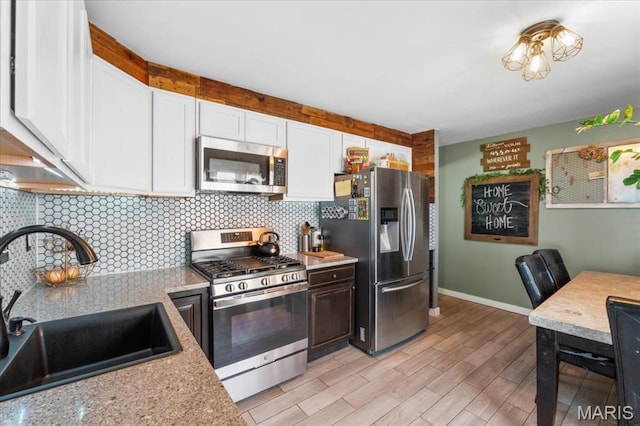 2851 Quenley St, Saint Charles, MO 63301 - kitchen with appliances with stainless steel finishes, a sink, light countertops, white cabinetry, and decorative backsplash