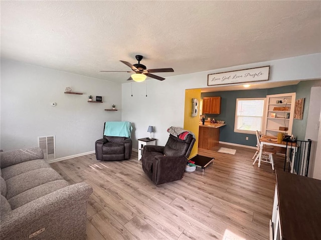 711 N Lindell St, Vandalia, MO 63382 - living room with light wood-type flooring, a ceiling fan, a textured ceiling, and baseboards