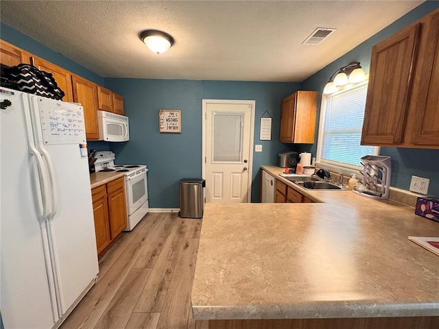 711 N Lindell St, Vandalia, MO 63382 - kitchen with white appliances, a sink, light wood-style floors, a textured ceiling, and brown cabinets