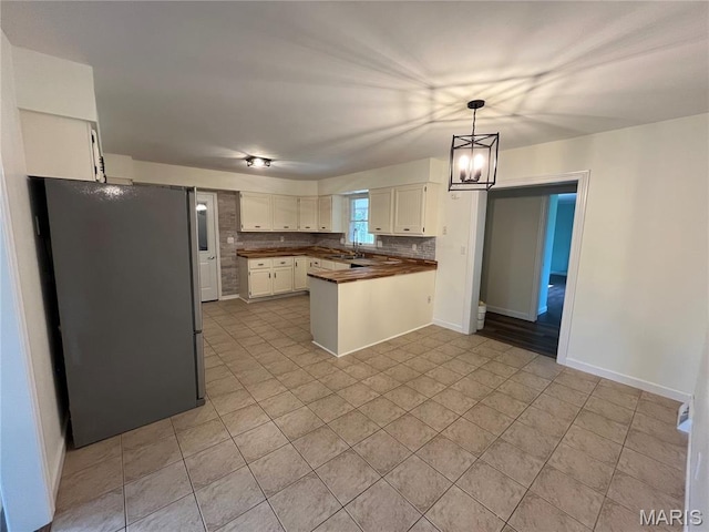 1319 W Main St, Bowling Green, MO 63334 - kitchen featuring freestanding refrigerator, a peninsula, dark countertops, a sink, and white cabinetry