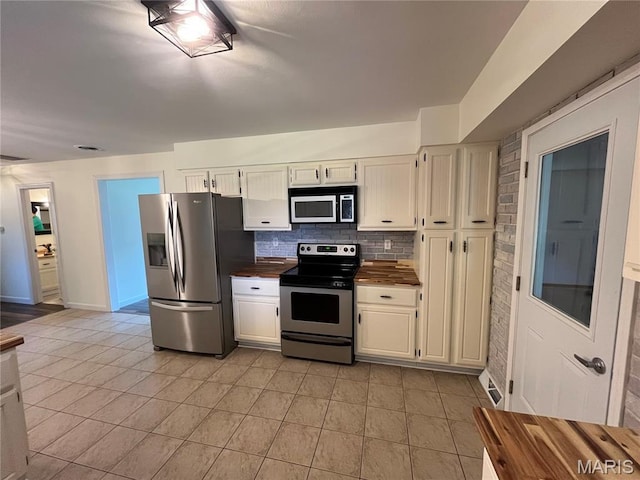 1319 W Main St, Bowling Green, MO 63334 - kitchen featuring stainless steel appliances, white cabinetry, decorative backsplash, light tile patterned floors, and baseboards