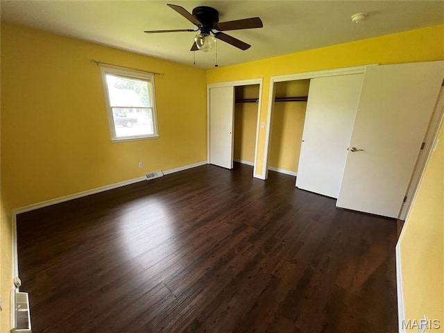 1319 W Main St, Bowling Green, MO 63334 - unfurnished bedroom with two closets, dark wood-style floors, baseboards, and ceiling fan