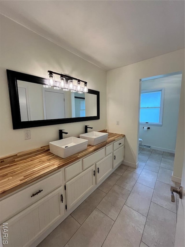 1319 W Main St, Bowling Green, MO 63334 - bathroom with double vanity, toilet, tile patterned floors, and baseboards