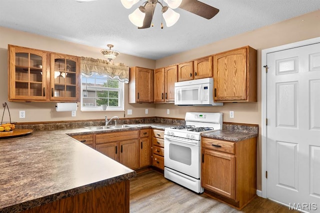 2711 Cascade Lake Dr, Shiloh, IL 62221 - kitchen with white appliances, a sink, dark countertops, glass insert cabinets, and light wood finished floors