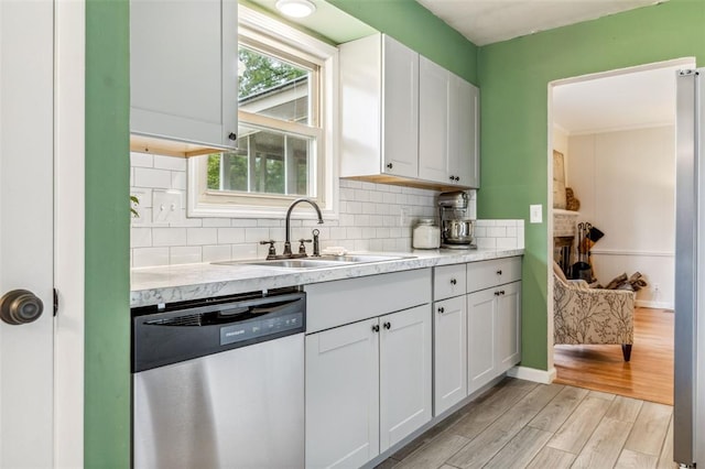 330 Mont Divier Dr, Bonne Terre, MO 63628 - kitchen with stainless steel dishwasher, a sink, light wood-style floors, tasteful backsplash, and white cabinetry