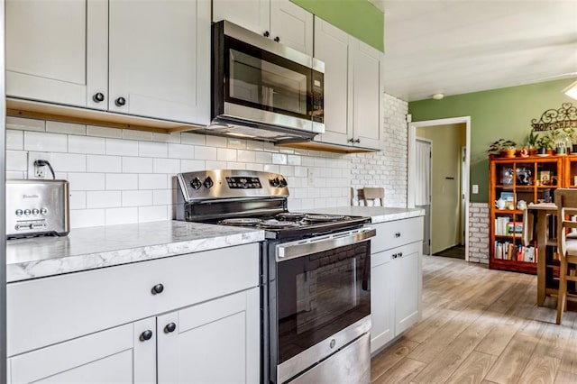 330 Mont Divier Dr, Bonne Terre, MO 63628 - kitchen with appliances with stainless steel finishes, light wood finished floors, light stone countertops, and tasteful backsplash