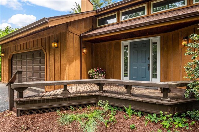 513 Matthews Ln, Waterloo, IL 62298 - view of exterior entry featuring a wooden deck, a chimney, board and batten siding, and a garage