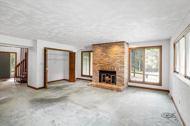 513 Matthews Ln, Waterloo, IL 62298 - unfurnished living room with plenty of natural light, baseboards, a brick fireplace, and a textured ceiling