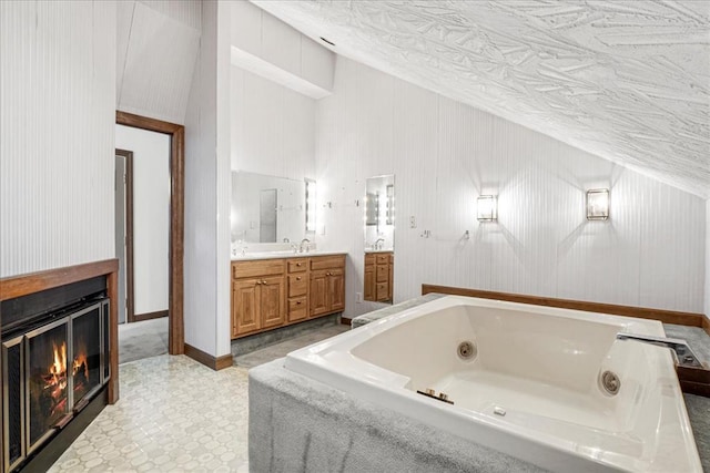 513 Matthews Ln, Waterloo, IL 62298 - bathroom featuring vanity, a tub with jets, lofted ceiling, a glass covered fireplace, and tile patterned floors