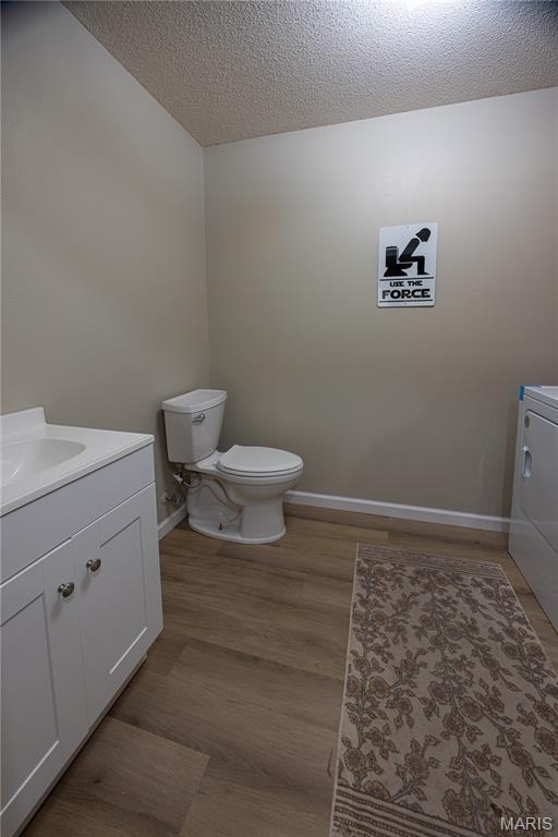 781 N W Ln, Jackson, MO 63755 - half bath featuring a textured ceiling, vanity, toilet, baseboards, and wood finished floors