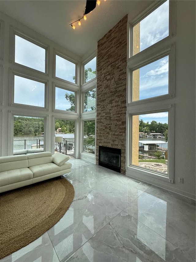 149 Thornwood Cir, Sunrise Beach, MO 65079 - unfurnished living room with a towering ceiling, a stone fireplace, marble tiled floors, and rail lighting