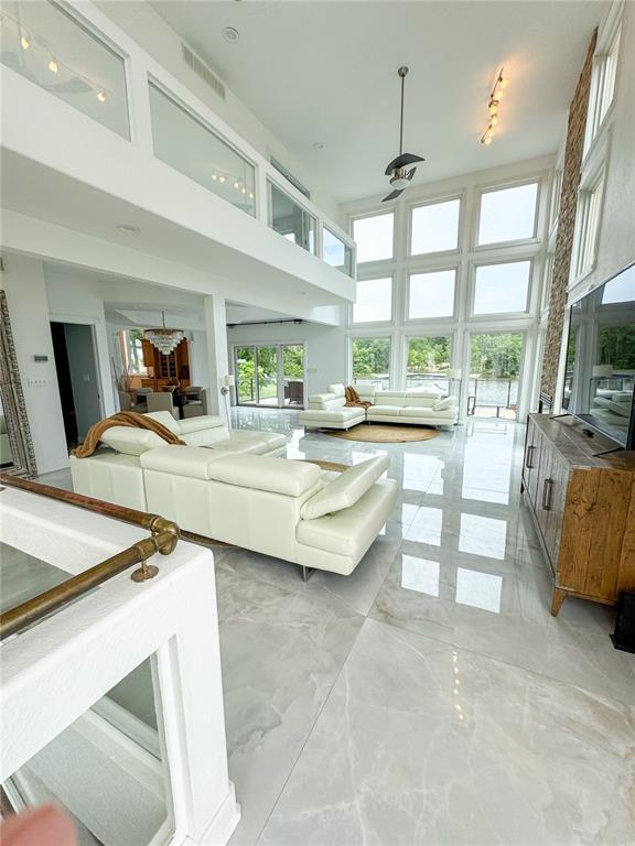 149 Thornwood Cir, Sunrise Beach, MO 65079 - living room featuring a high ceiling, a ceiling fan, and light marble finish floors