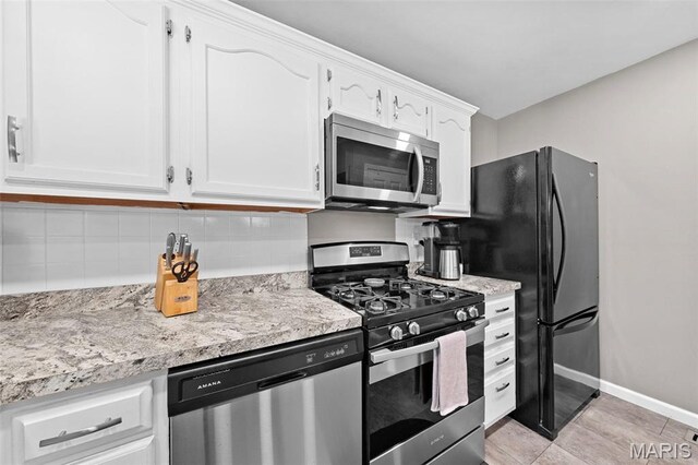 2917 Royal Gorge Ct, Oakville Township, MO 63129 - kitchen featuring appliances with stainless steel finishes, white cabinetry, backsplash, baseboards, and light stone counters