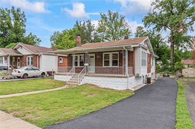 8838 Argyle Ave, Overland, MO 63114 - view of front facade with a porch, a chimney, brick siding, a front lawn, and driveway
