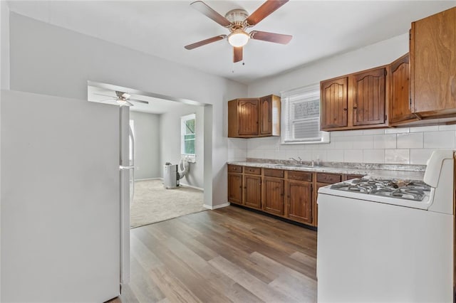 8838 Argyle Ave, Overland, MO 63114 - kitchen with white appliances, ceiling fan, brown cabinets, backsplash, and light countertops