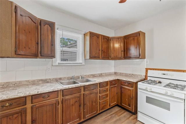 8838 Argyle Ave, Overland, MO 63114 - kitchen with white gas range oven, a sink, light wood-style floors, and light countertops