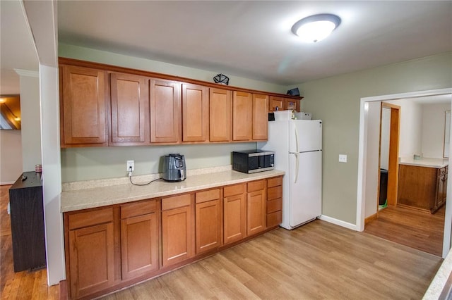 155 Roberts St, Jerseyville, IL 62052 - kitchen with stainless steel microwave, freestanding refrigerator, light wood-style flooring, and light countertops