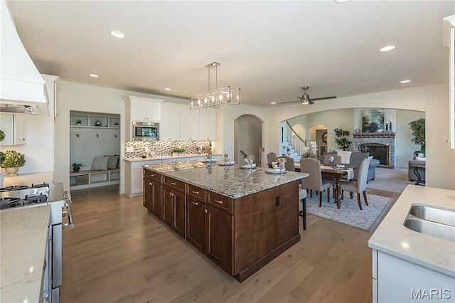 111 N Mosley Rd, Saint Louis, MO 63141 - kitchen with custom range hood, stainless steel appliances, a ceiling fan, dark brown cabinets, and arched walkways