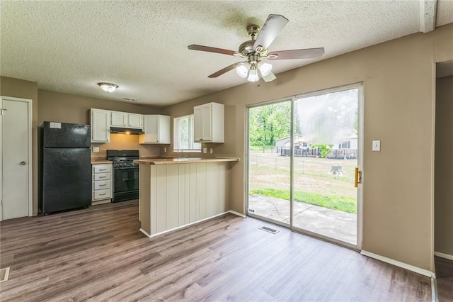 6250 Pennyrich Ct, Florissant, MO 63033 - kitchen with black appliances, wood finished floors, under cabinet range hood, a textured ceiling, and a peninsula
