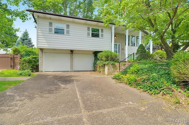 2631 Georgia Dr, Arnold, MO 63010 - raised ranch featuring a garage, concrete driveway, brick siding, and stairway