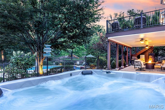 4388 Austin Pass Dr, Saint Charles, MO 63304 - pool at dusk featuring an outdoor fire pit, a ceiling fan, a hot tub, stairway, and a patio area