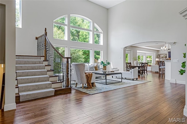 4388 Austin Pass Dr, Saint Charles, MO 63304 - living room with arched walkways, a high ceiling, a chandelier, wood-type flooring, and stairway
