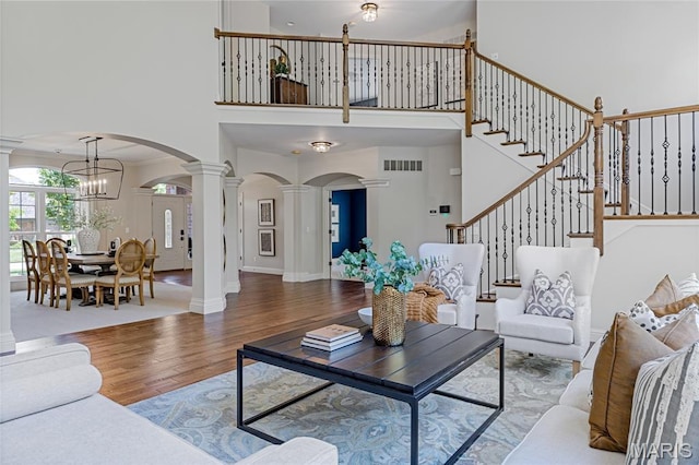 4388 Austin Pass Dr, Saint Charles, MO 63304 - living room featuring decorative columns, arched walkways, wood finished floors, a high ceiling, and a chandelier