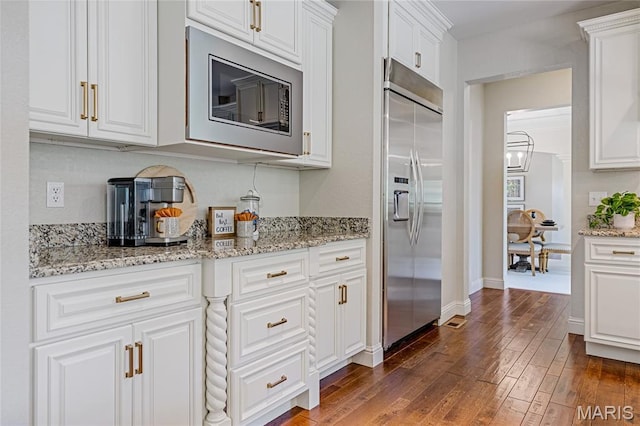 4388 Austin Pass Dr, Saint Charles, MO 63304 - kitchen featuring built in appliances, white cabinets, dark wood-style flooring, and light stone counters
