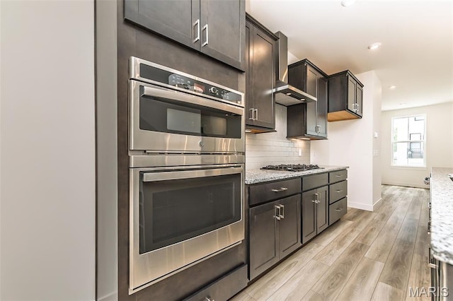 8916 Gateway Cir Unit 41-805, Richmond Heights, MO 63144 - kitchen with stainless steel appliances, light wood-style flooring, tasteful backsplash, wall chimney exhaust hood, and recessed lighting