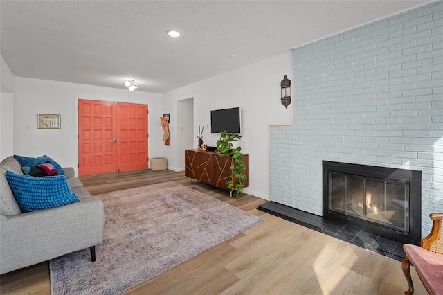 1594 Rue Calais, Bonne Terre, MO 63628 - living room with wood finished floors, a brick fireplace, recessed lighting, a textured ceiling, and baseboards