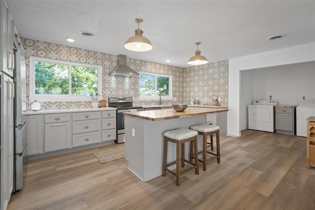 1594 Rue Calais, Bonne Terre, MO 63628 - kitchen with washer / dryer, electric stove, wall chimney range hood, butcher block counters, and wallpapered walls