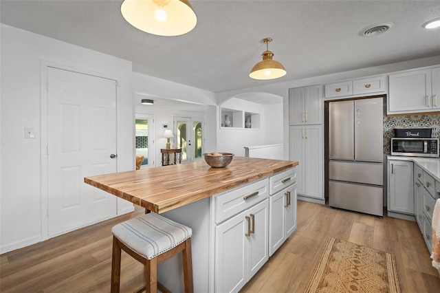 1594 Rue Calais, Bonne Terre, MO 63628 - kitchen featuring stainless steel appliances, butcher block countertops, arched walkways, a kitchen bar, and light wood-style flooring