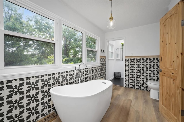 1594 Rue Calais, Bonne Terre, MO 63628 - bathroom featuring tile walls, a freestanding bath, a wainscoted wall, wood finished floors, and toilet