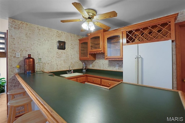 238 Skyway Dr, New Haven, MO 63068 - kitchen featuring white fridge, dark countertops, glass insert cabinets, a ceiling fan, and brown cabinets